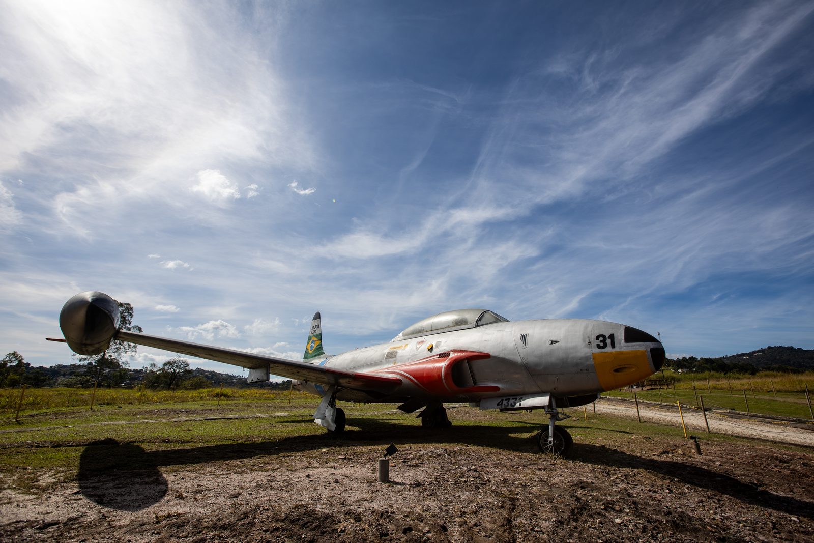 Avião de caça exposto ao ar livre no Instituto da Costela, sob céu de nuvens finas