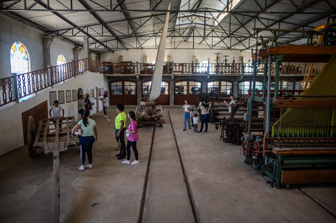 Visitantes caminhando pelo galpão do museu entre máquinas industriais antigas