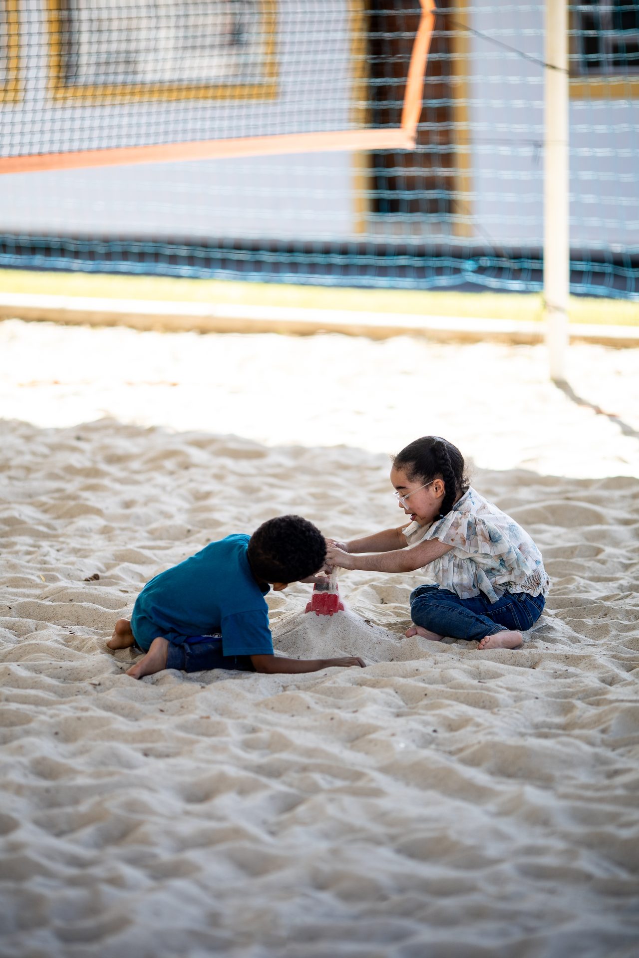 Duas crianças brincando na areia da quadra de beach tênis e futevôlei