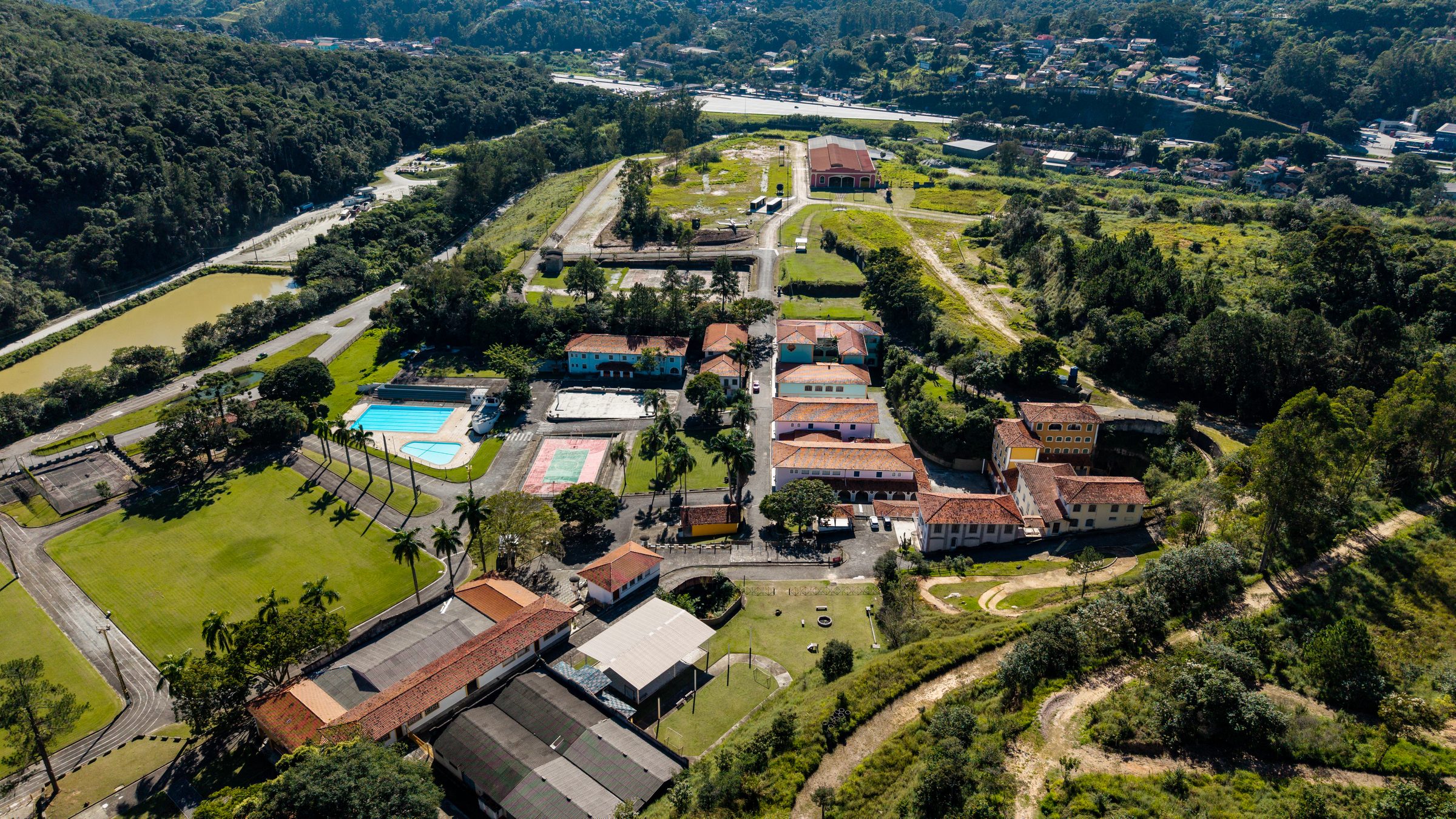 Vista aérea do Instituto da Costela em Mairiporã, com as piscinas, os casarões amarelos, os campos gramados e a serra ao redor